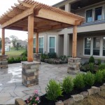 wooden pergola with stone posts outside two story home and landscaped yard