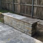 Stone bench in backyard by wooden fence