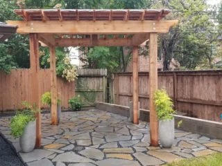 Silvermist Flagstone Patio with blackstar Gravel Joints and Cedar Pergola. Masonry Block Sitting Wall